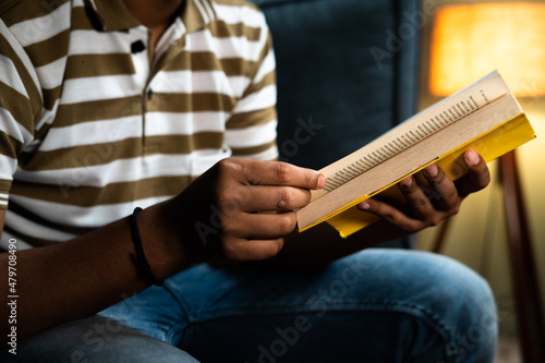 Fotografi Focus on book unrecognazible young man studying book before going to sleep - con