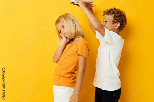 a boy with a comb combing a girl's hair yellow background