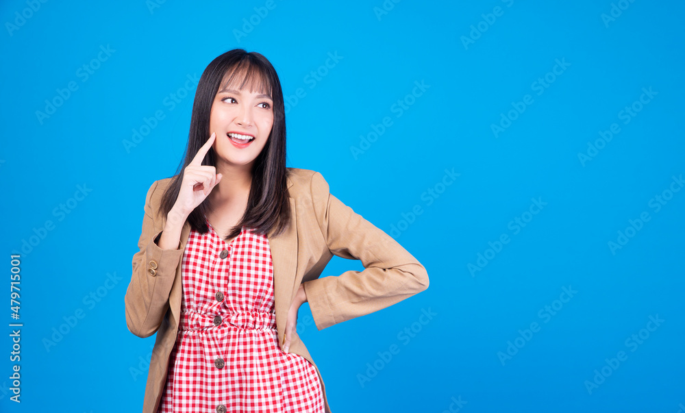 Confidence business positive Asian young woman thinking have good idea holding finger under chin while looking at copy space standing over isolated blue background. Confidence business positive Asian young woman thinking have good idea holding finger under chin while looking at copy space standing over isolated blue background.