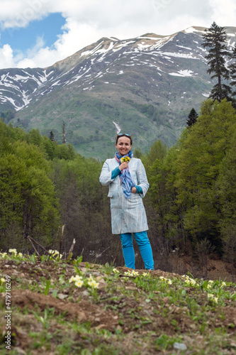 Beautiful Young Woman Posing with Bouquet of Spring Wild Flowers by the Caucasus Mountains