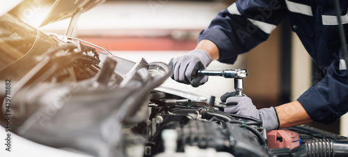 Mechanic works on the engine of the car in the garage. Repair service. Concept of car inspection service and car repair service.