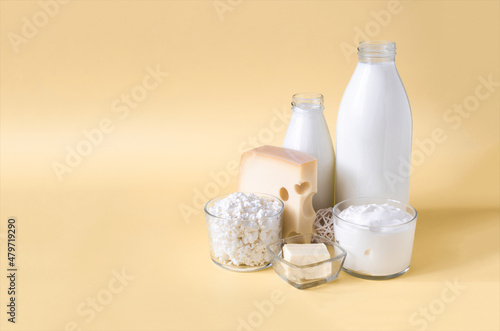 A set of milk products on a yellow background. Milk  kefir  sour cream  cheese  butter and cottage cheese in a glass container on a light background place for text