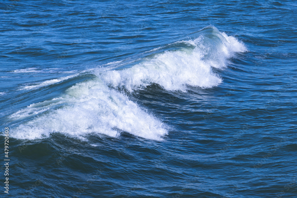 Wave with white foam goes over deep blue sea water Wave with white foam goes over deep blue sea water