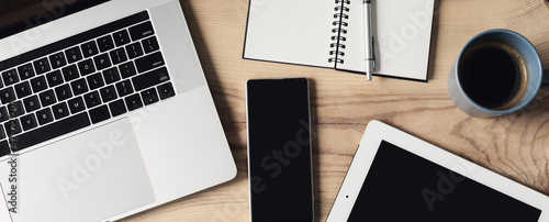 Smartphone, laptop computer, digital tablet on wooden office desk, top view, panoramic banner. Business, technology, application, web site, mockup, home office, e-learning concept