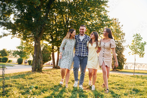 Man with three women standing in the park and embracing