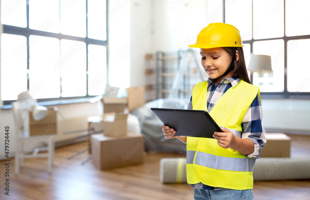 building, construction and profession concept - smiling little girl in protective helmet and safety vest with tablet pc computer over stuff in living room on background building, construction and profession concept - smiling little girl in protective helmet and safety vest with tablet pc computer over stuff in living room on background