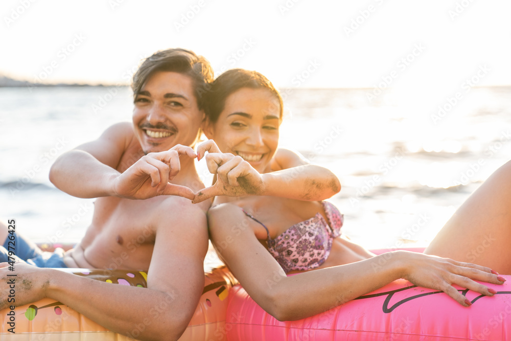 Photoshoot of young helthy beautiful caucasian couple, boy and girl, dating at the beach - Man and woman lovers having fun in holidays sunbathing near the ocean in a sunny day looking at each others