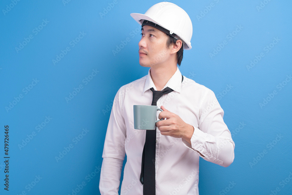 Portrait of confident male engineer wearing a white helmet having a cup of coffee over purple background studio Portrait of confident male engineer wearing a white helmet having a cup of coffee over purple background studio