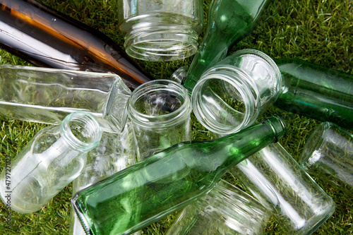 recycling, garbage disposal, environment and ecology concept - close up of empty used glass bottles and jars on grass photo