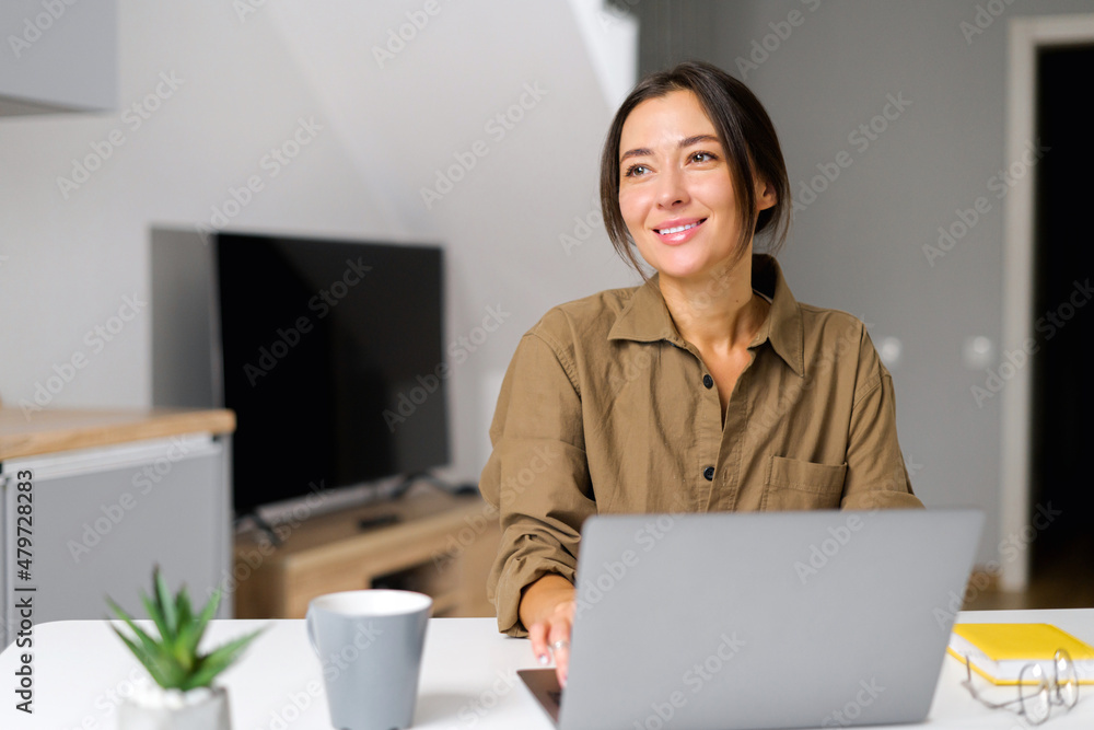 Inspired young Asian multiracial woman sitting at the desk at home office with a laptop, making a wishlist, dreaming, and planning her vacation, looking for new ideas for the project Inspired young Asian multiracial woman sitting at the desk at home office with a laptop, making a wishlist, dreaming, and planning her vacation, looking for new ideas for the project