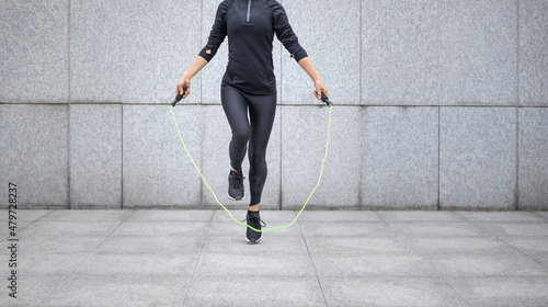 Photography Fitness woman rope skipping against city wall