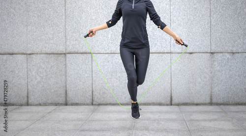Canvas Print Fitness woman rope skipping against city wall