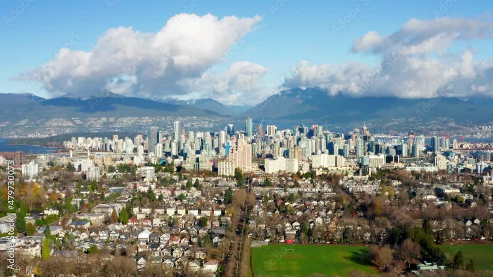 The Beautiful City of Vancouver and the North Shore Mountains, aerial view flying backwards on a gorgeous blue sky day with fluffy clouds The Beautiful City of Vancouver and the North Shore Mountains, aerial view flying backwards on a gorgeous blue sky day with fluffy clouds