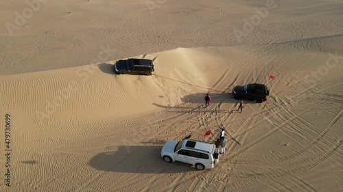 4K: Drone view of the group of 4x4 helping a stuck vehicle in the sand during the desert safari in the Al Qudra desert of Dubai, United Arab Emirates photo