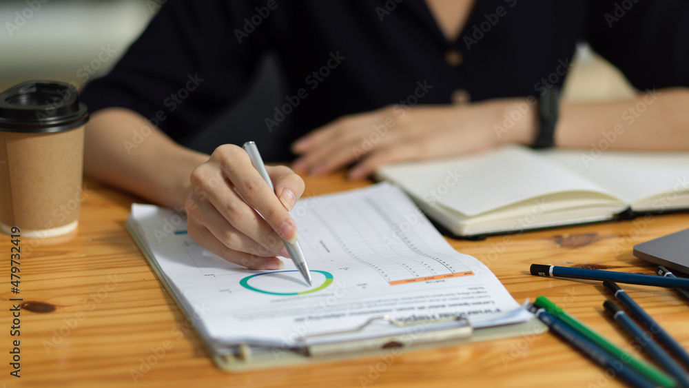 Cropped image of a financial worker analysing financial data on the report Cropped image of a financial worker analysing financial data on the report