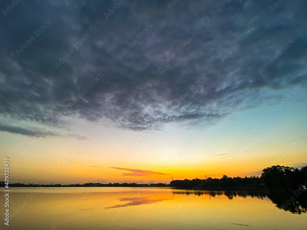 Naklejka premium Sunrise reflection, huge cloud over lake