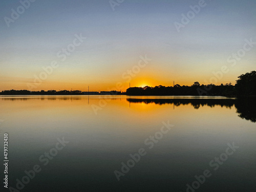 Sunrise reflection on the horizon over lake © Christopherab