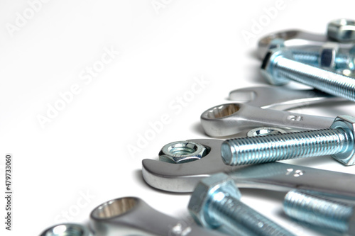 several open-end metal wrenches for working with bolts. Close-up on a white background. Silver metal fixing bolts and nuts. Copy space