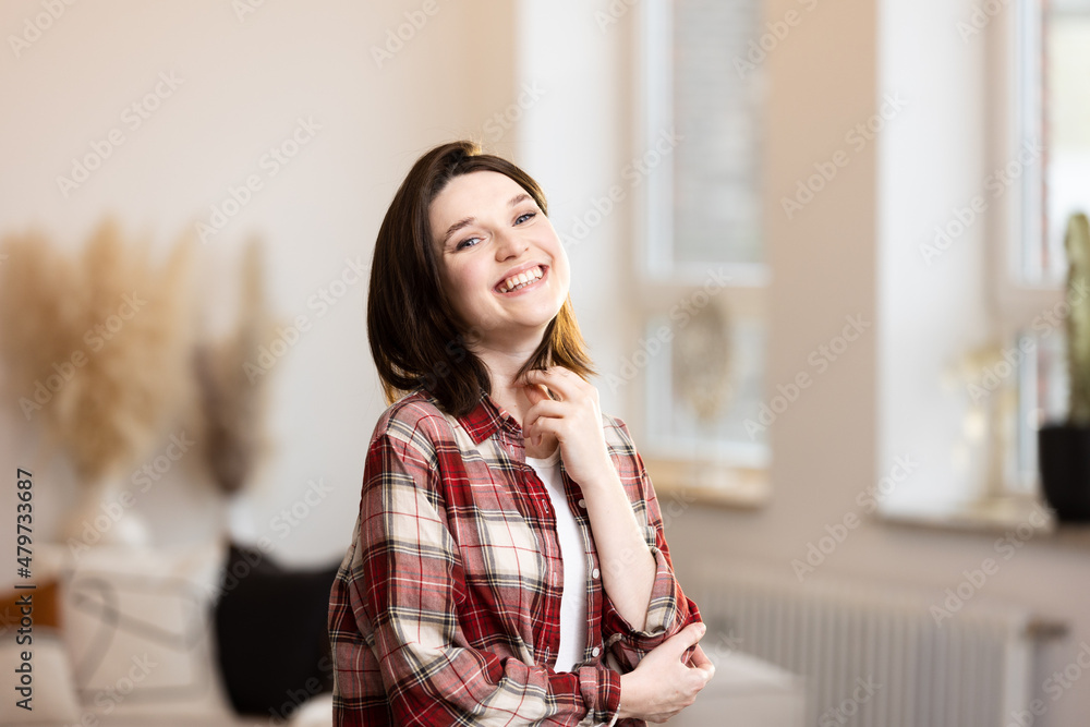 Happy young woman smiling at the camera at home, successful female with positive emotions