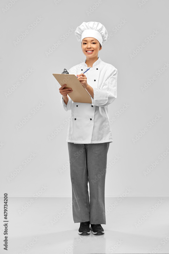 cooking, culinary and people concept - happy smiling female chef with clipboard and pen over grey background cooking, culinary and people concept - happy smiling female chef with clipboard and pen over grey background