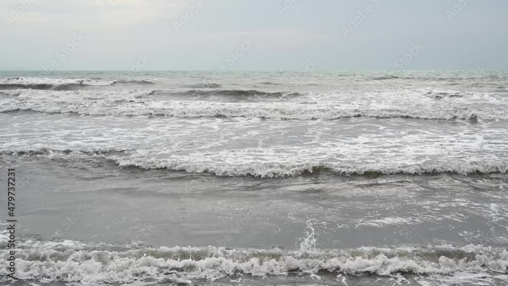 Muddy sea water after the rain. Stormy weather on the coast. Waves of the sea with sandy brown and grey color. Muddy sea water after the rain. Stormy weather on the coast. Waves of the sea with sandy brown and grey color.