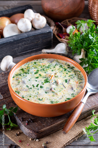 Mushroom Cheese Soup in a bowl and ingredients on a wooden table, vertical view from above
