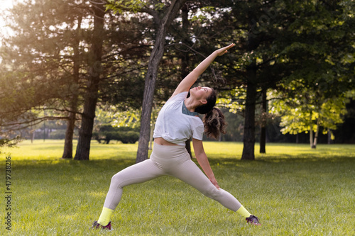 Young female practising yoga in public park at sunrise