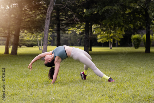 Young female practising yoga in public park at sunrise