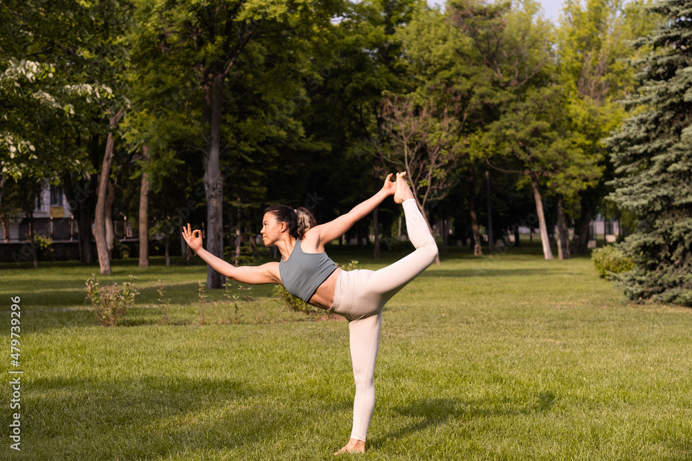 Young female practising yoga in public park at sunrise Young female practising yoga in public park at sunrise