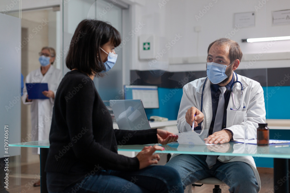 Obraz premium Specialist giving prescription paper with medicine to woman, signing checkup document. Doctor and patient talking about treatment and medication at consultation during covid 19 pandemic.