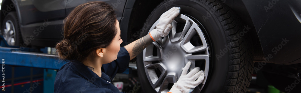 Young mechanic holding disk of car wheel in service, banner. Young mechanic holding disk of car wheel in service, banner.