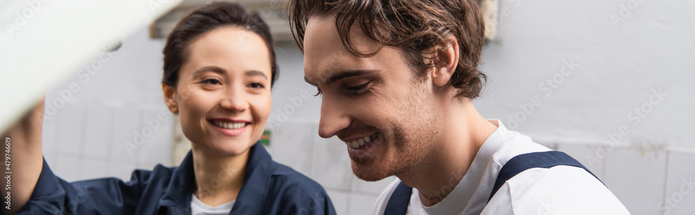 Positive mechanic standing near workwoman in car service, banner. Positive mechanic standing near workwoman in car service, banner.