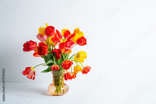 Big flowers bouquet of multicolored tulips in vintage glass vase on white color background with copy space. Business card. Invitation postcard. Place for greeting text. International holiday. Banner