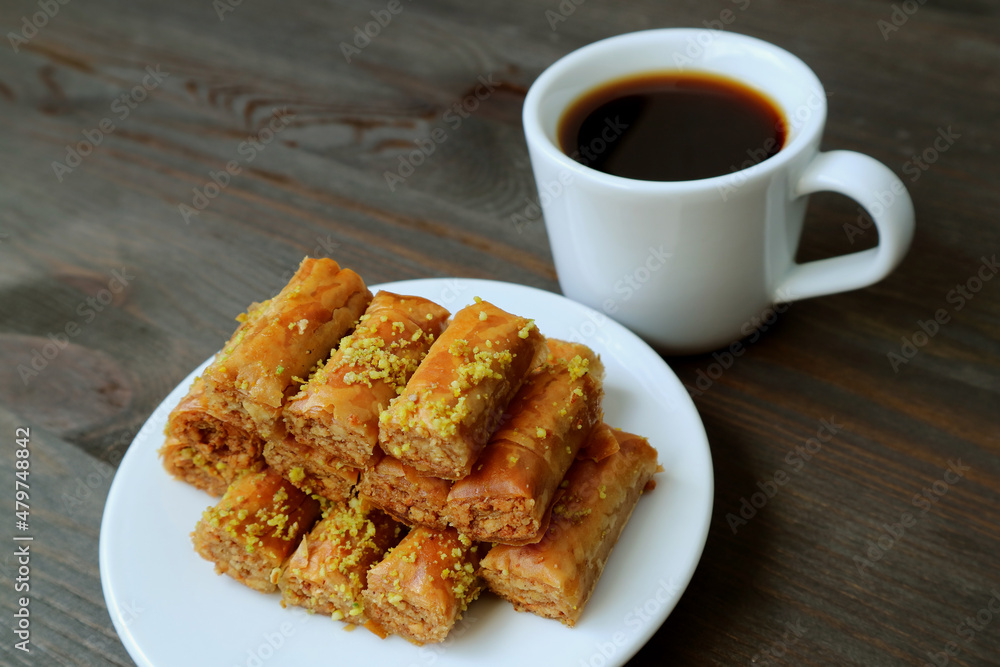 Plate of Pistachio Nuts Baklava Pastries with a Cup of Hot Coffee on Black Wooden Table Plate of Pistachio Nuts Baklava Pastries with a Cup of Hot Coffee on Black Wooden Table