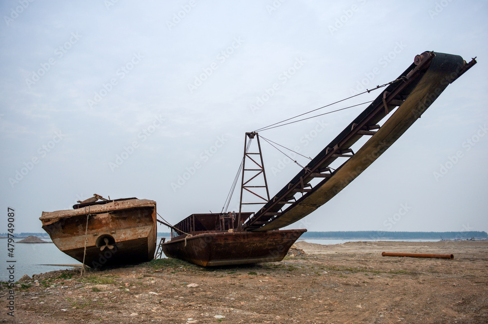 Abandoned rusty dredgers parked along riverbanks. Abandoned rusty dredgers parked along riverbanks.