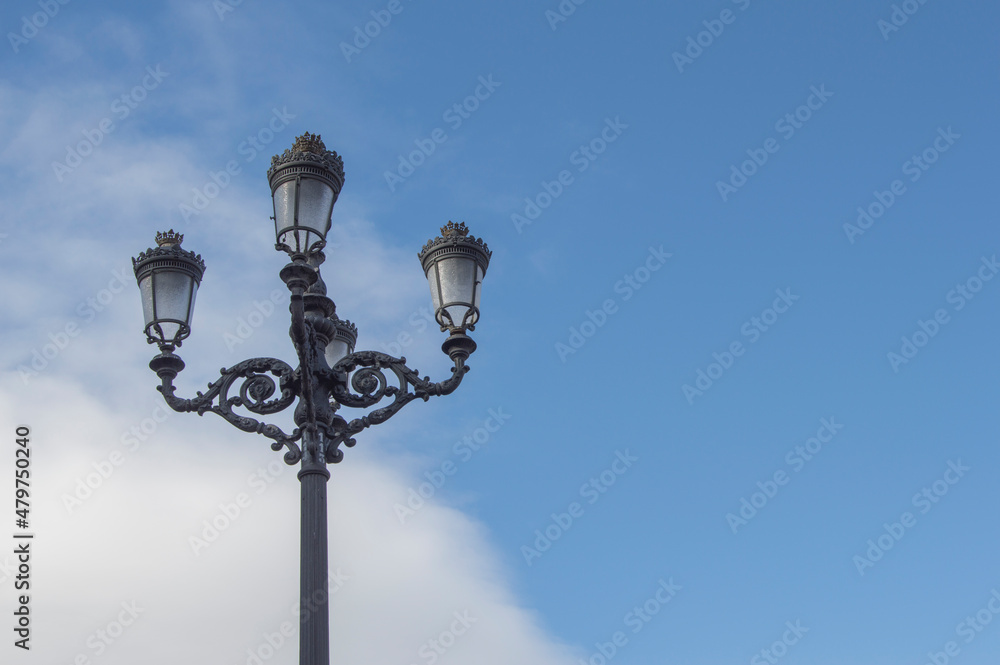 A Fernandina-style lamppost on blue sky in a park in Madrid. Spain