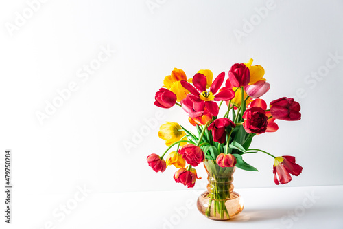 Big flowers bouquet of multicolored tulips in vintage glass vase on white color background with copy space. Business card. Invitation postcard. Place for greeting text. International holiday. Banner