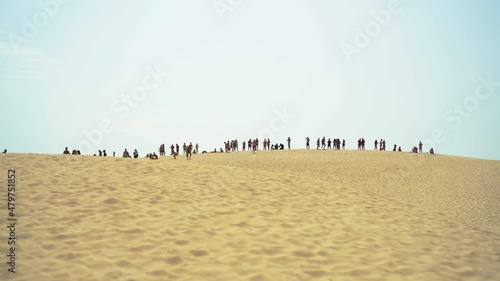 Duna de arena con siluetas de mucha gente en la parte superior 
