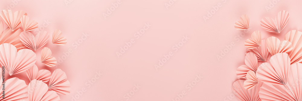 Valentines day banner - pink paper ribbed hearts fly on soft light pastel pink background as sideways border with copy space, top view. Festive love backdrop for card, design, website, advertising.