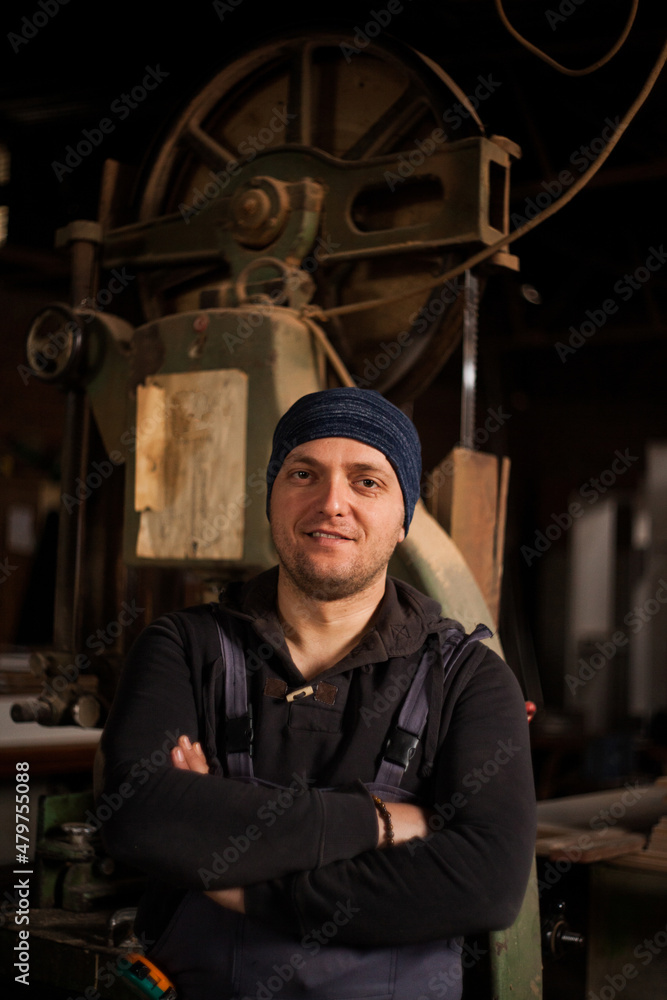 Young male carpenter standing in his work shop Young male carpenter standing in his work shop