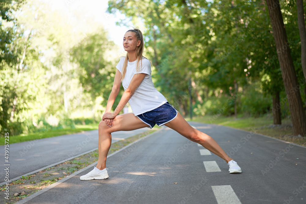 Woman runner stretching legs before exercising summer park morning Woman runner stretching legs before exercising summer park morning