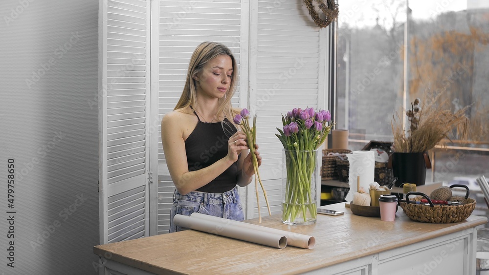 A young beautiful woman engaged in floristry begins to collect the best flowers for her flower arrangement. Floristry