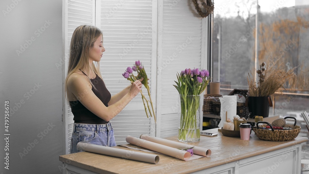 A young beautiful woman engaged in floristry begins to collect the best flowers for her flower arrangement. Floristry A young beautiful woman engaged in floristry begins to collect the best flowers for her flower arrangement. Floristry