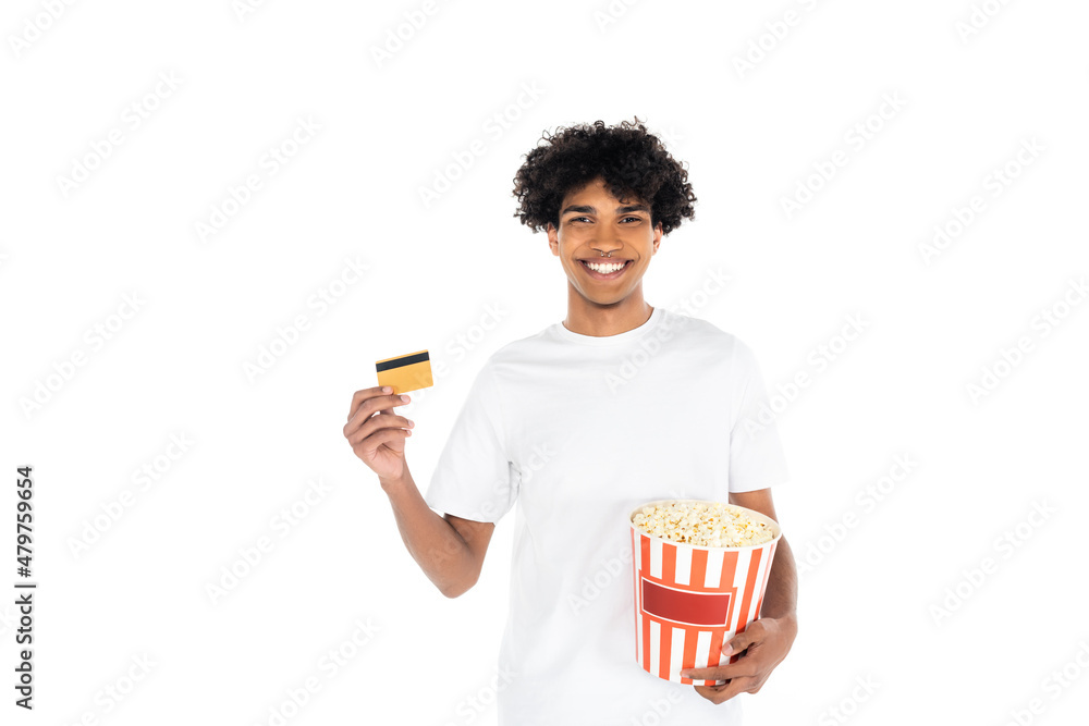 pleased african american man holding bucket of popcorn and credit card isolated on white. pleased african american man holding bucket of popcorn and credit card isolated on white.