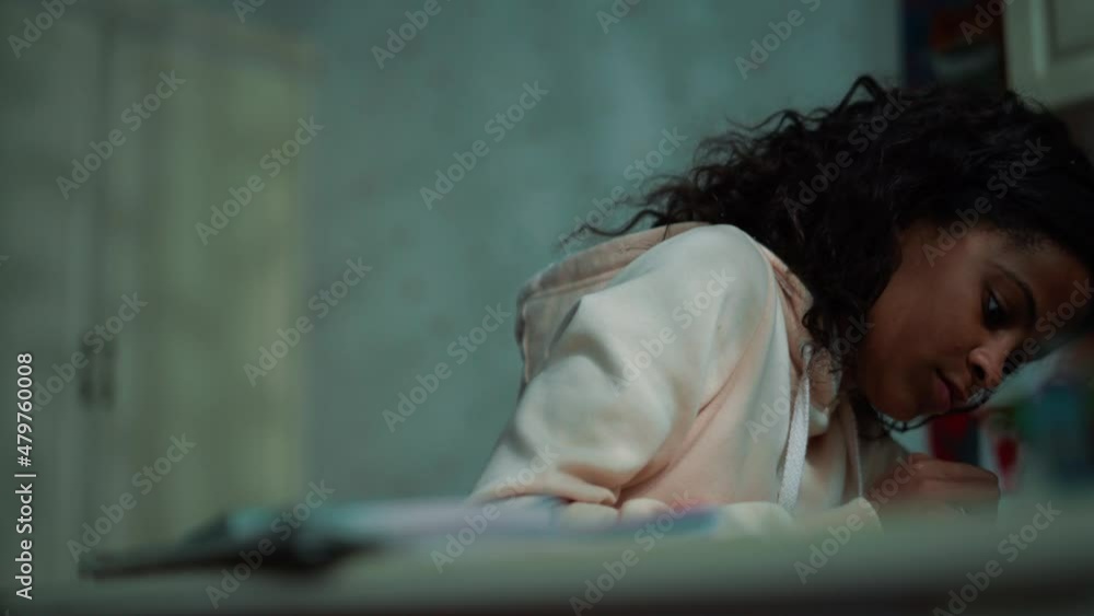 Meditative African young girl doing homework at home Meditative African young girl doing homework at home