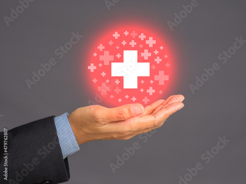 Health care and business health insurance concept. Virtual medical icons on the palm businessman against a gray background