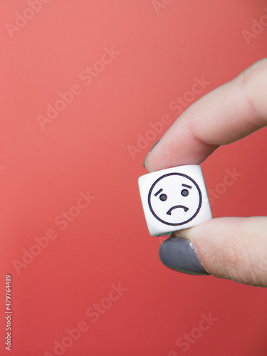 dice with sad face and red background. Concept and emotion.