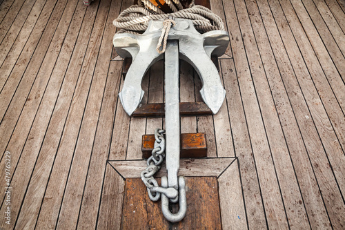 The anchor lies on the wooden deck of the ship.