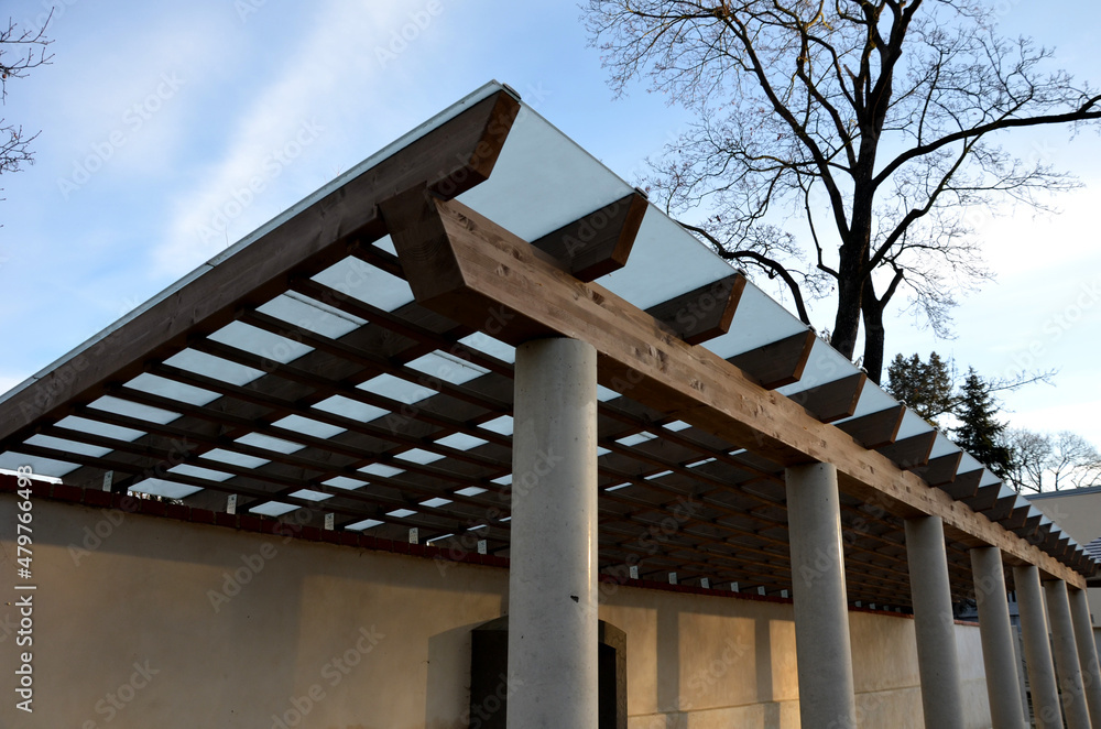 Foto Stock wooden structure of the pergola supported by smooth cylindrical  white columns shelter of a gazebo pergola. roof lined with glass. connects  to the retaining wall with a brick roof
