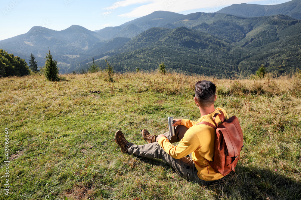 Tourist with thermos and backpack enjoying beautiful mountain landscape Tourist with thermos and backpack enjoying beautiful mountain landscape